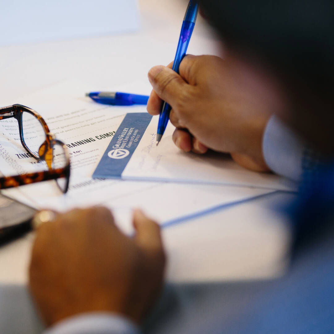 A person writing notes with a pen and paper.